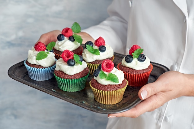 Nahaufnahme auf den Händen des weiblichen Chefs ein Tellersegment der verzierten Schokoladenkleinen kuchen anhalten