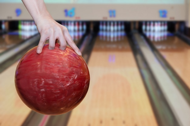 Nahaufnahme auf der Frauenhand, die Bowlingkugel gegen Bowlingbahn hält