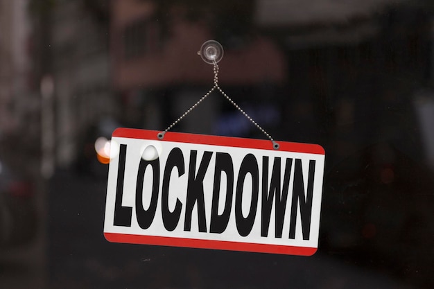 Nahaufnahme auf einem geschlossenen Schild im Schaufenster eines Ladens mit der Meldung LockdownxA