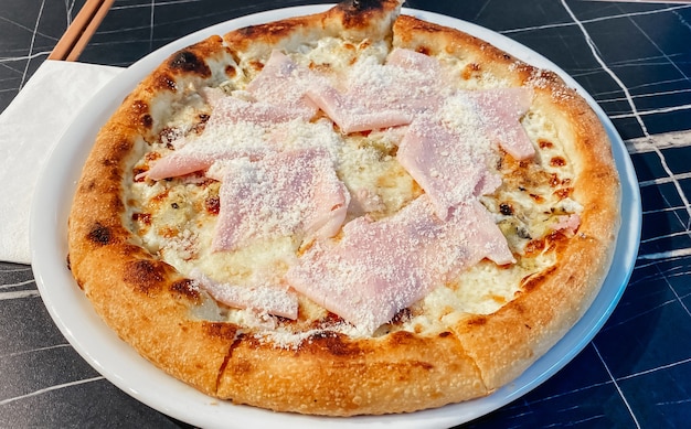 Nahaufnahme auf einer Restauranttischpizza mit Prosciutto Cotto und Taleggio-Käse. Lebensmittelkonzept.