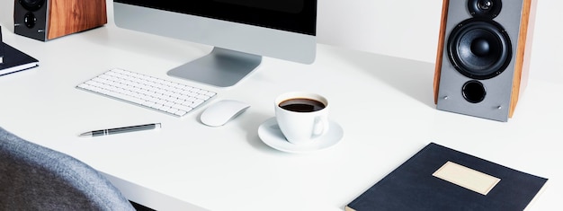 Nahaufnahme auf einer Tasse Kaffee neben einer Computermaus und -tastatur auf einem weißen Schreibtisch in einem Innenraum für einen Freiberufler Echtes Foto