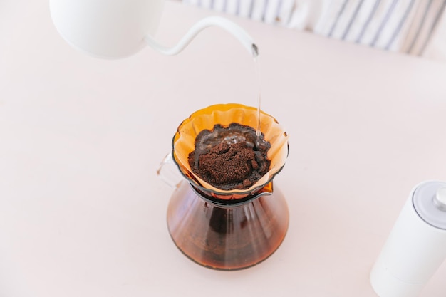 Nahaufnahme auf gemahlenem Kaffee über dem Papierfilter Übergießen auf gemahlenem Kaffee über dem Papierfilter auf einem Glastropfer Eine alternative Methode heißt Dripping