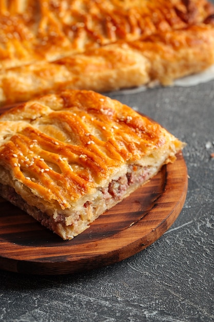 Nahaufnahme auf geschnittenem Kuchen mit Rindfleisch- und Kartoffelfüllung auf dem Holztisch