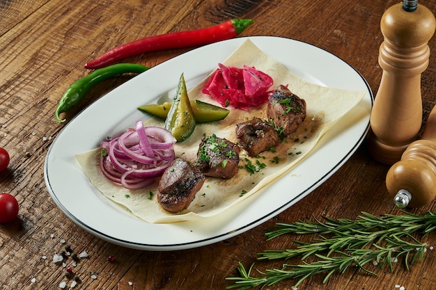 Nahaufnahme auf leckeres gegrilltes Fleisch mit Gemüse auf georgischer Pita. Schaschlik oder Grillfleisch auf Pita. Schaschlik, traditionelles Essen der georgischen Küche. Kopieren Sie Platz für Design. Holzoberfläche