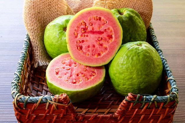 Nahaufnahme auf rote Guave geschnitten mit grünem Blatt auf rustikalem Holztisch