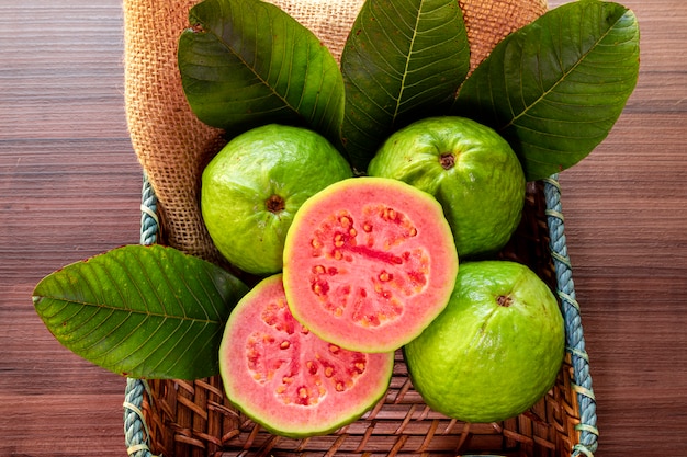 Nahaufnahme auf rote Guave geschnitten mit grünem Blatt auf rustikalem Holztisch
