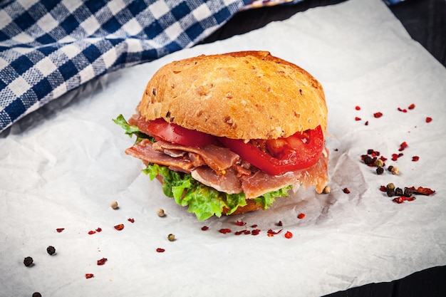 Nahaufnahme auf Sandwich mit Schinken, Salat, Tomate auf weißer Oberfläche