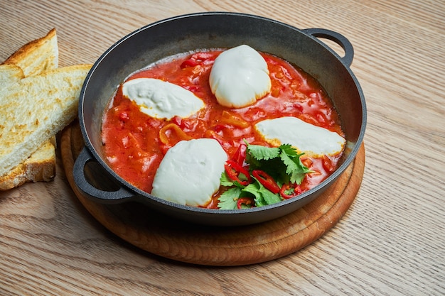 Nahaufnahme auf Shakshuka mit heißem Chili-Pfeffer in Tomatensaft mit der Zugabe von Kichererbsen, Käse und Paprika. Traditionelle israelische Küche