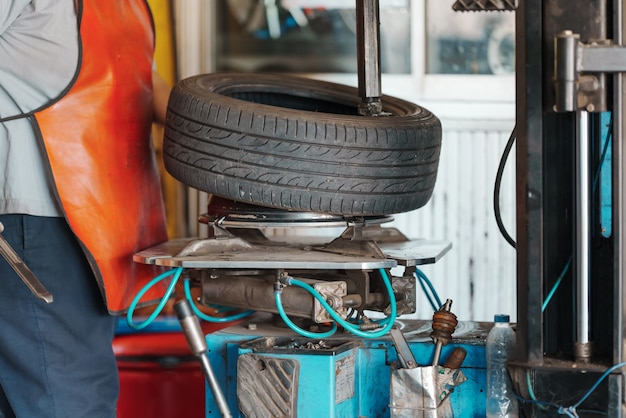 Nahaufnahme Automechaniker ersetzen Reifen am Rad in der Autowerkstatt.