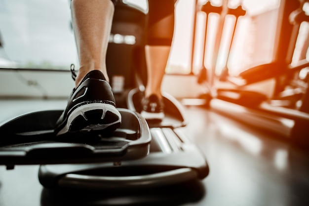 Nahaufnahme Bein des Cardio-Trainings auf einem EllipsentrainerMenschen trainieren auf einem Ellipsentrainer im FitnessstudioRückansicht