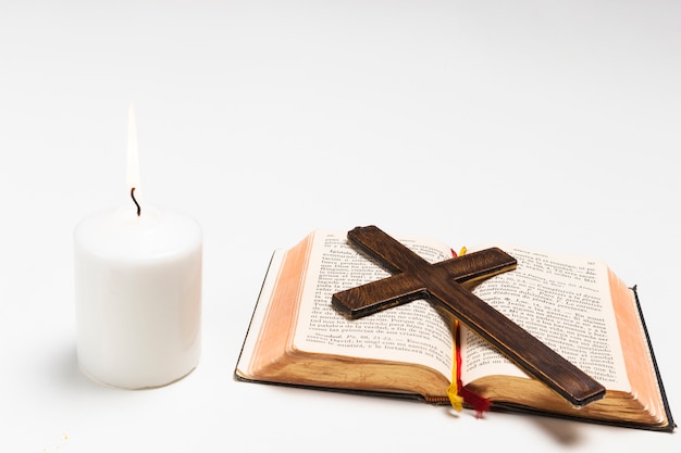 Foto nahaufnahme beleuchtete kerze mit heiliger schrift und kreuz