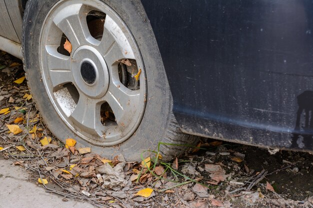 Nahaufnahme beschädigter Reifen. Das Rad des Autoreifens undicht. Reifenpanne wartet auf Reparatur. Verlassenes Auto auf dem Parkplatz.