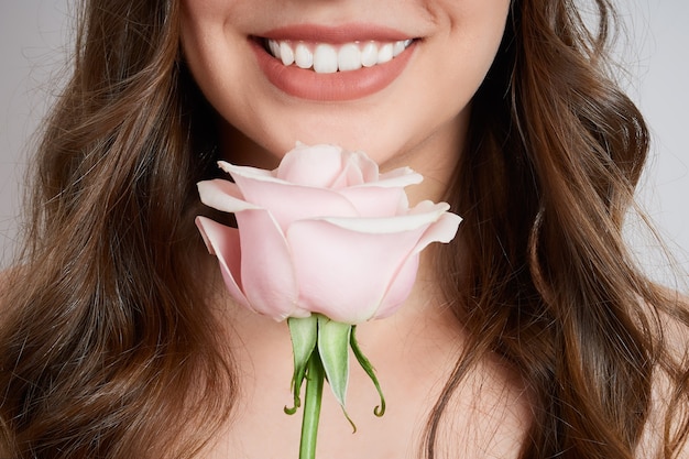 Nahaufnahme beschnittenes Porträt der lächelnden Frau mit rosa Rose nahe Gesicht