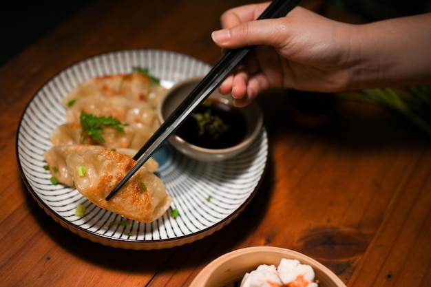 Nahaufnahme Bild Frauen essen köstliche chinesische gebratene Knödel mit Stäbchen auf einem Holztisch