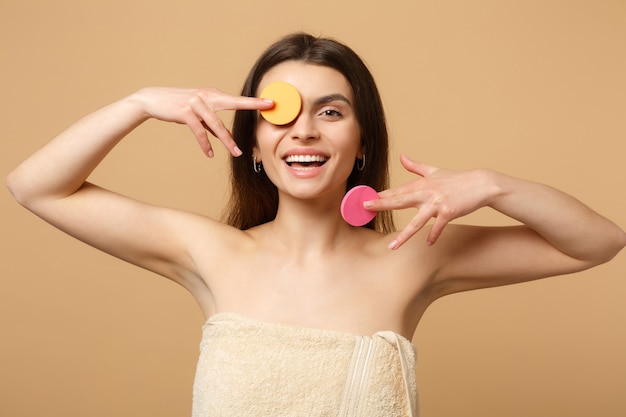 Nahaufnahme brünette halbnackte Frau mit perfekter Haut, nacktes Make-up entfernen isoliert auf beige pastellfarbener Wand