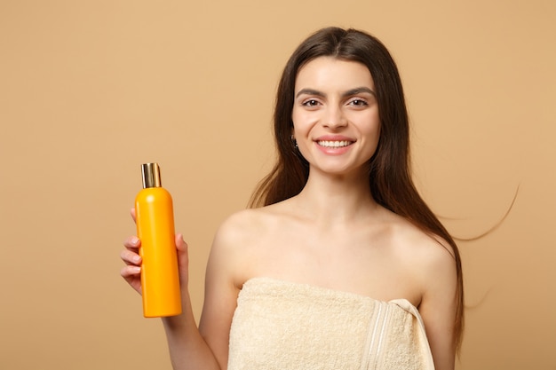 Nahaufnahme brünette halbnackte Frau mit perfekter Haut, nacktes Make-up isoliert auf beige pastellfarbener Wand