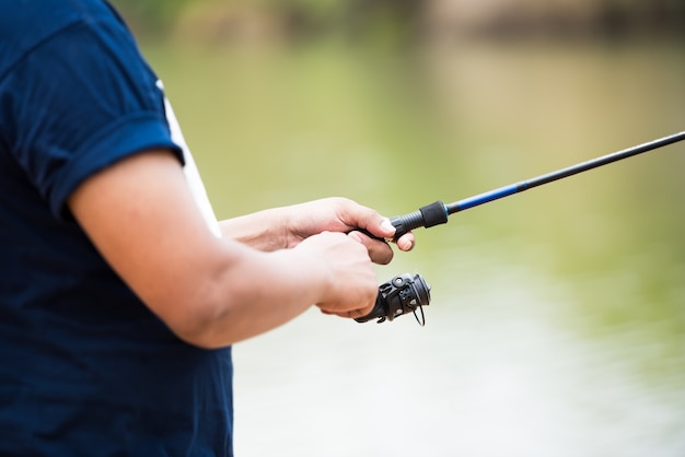 Nahaufnahme der Anglermannhand, die am Teich fischt