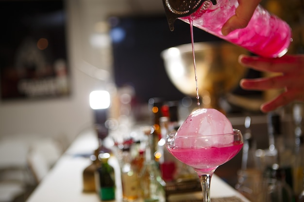 Nahaufnahme der Barkeeper-Hand, die rosa Cocktailgetränk in der Bar gießt?