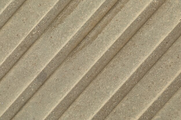 Nahaufnahme der beige-grauen Betonoberfläche mit diagonalen Streifen