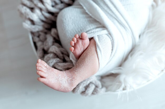 Nahaufnahme der Beine eines kleinen Neugeborenen auf einem zarten weißen Hintergrund, die Geburt eines Babys, eine glückliche Familie
