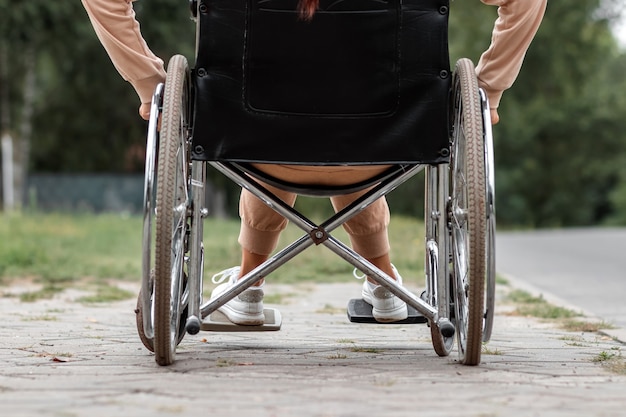 Foto nahaufnahme der beine im rollstuhl. das mädchen ist behindert. das konzept eines rollstuhls, einer behinderten person, eines vollen lebens, einer gelähmten, einer behinderten person, einer gesundheitsversorgung.