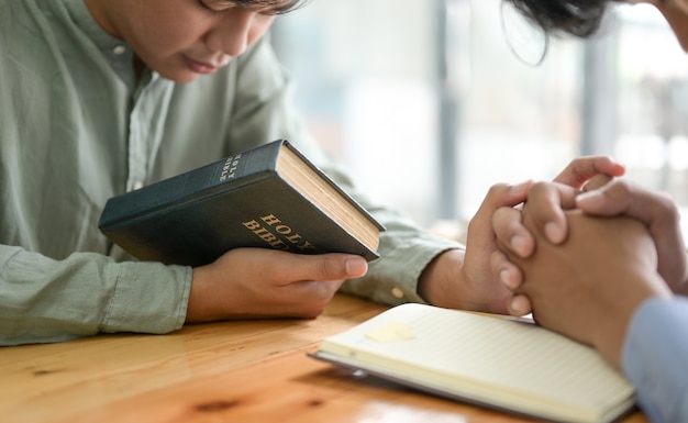 Nahaufnahme der Bibel und der betenden Menschen