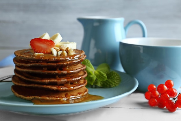 Nahaufnahme der blauen Platte mit köstlichen Schokoladenpfannkuchen verziert mit Erdbeere und Banane