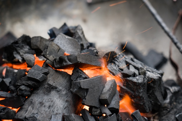 Nahaufnahme der brennenden Holzkohle. Kohle in Feuer und Rauch.