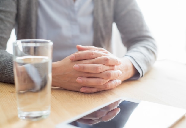 Nahaufnahme der Frau bei Tisch mit Tablet und Wasser