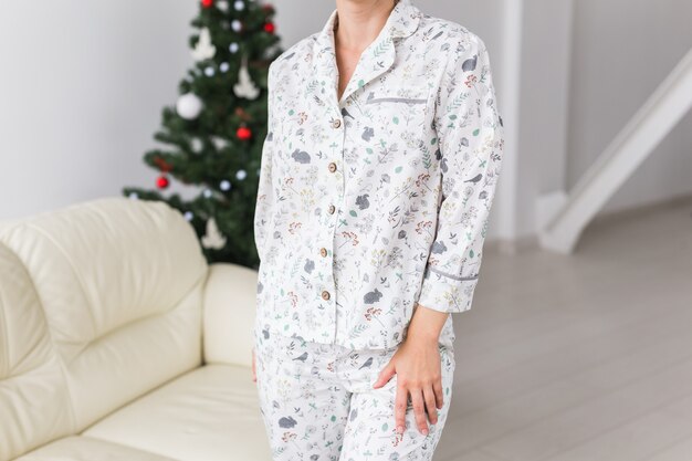 Nahaufnahme der frau mit pyjama mit schönem hund im wohnzimmer mit weihnachtsbaum. urlaub konzept.