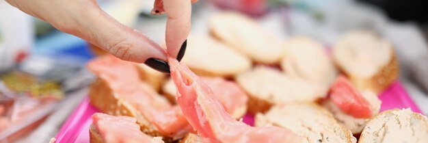 Nahaufnahme der Frauenhand, die Vorspeisenscheiben Baguette mit Fischstücken köstlichen Snack an sich nimmt