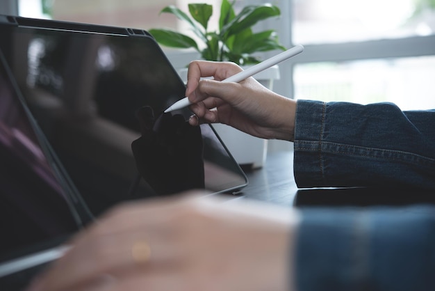 Nahaufnahme der Frauenhand mit Stylus-Stift, der den digitalen Tablet-Bildschirm berührt