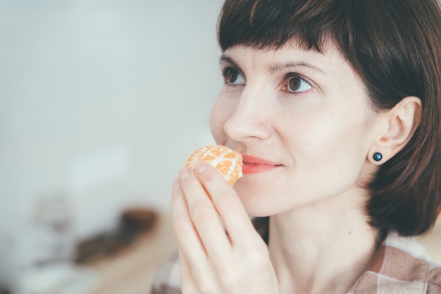 Nahaufnahme der glücklichen Frau, die eine Mandarine einatmet