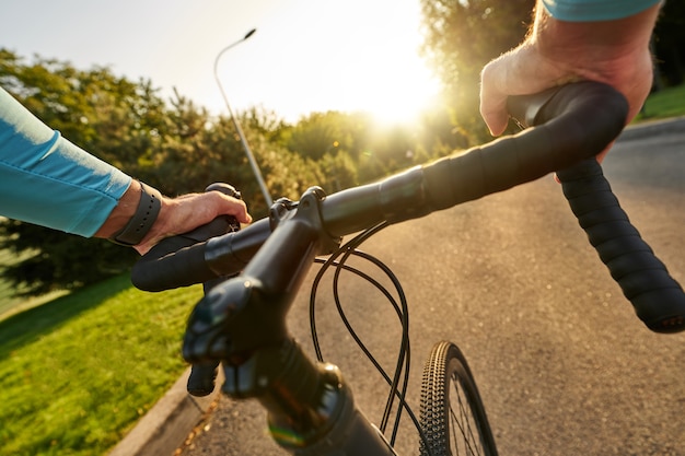 Nahaufnahme der Hände am Lenker eines professionellen Fahrradrennfahrers, der sein Rennrad fährt