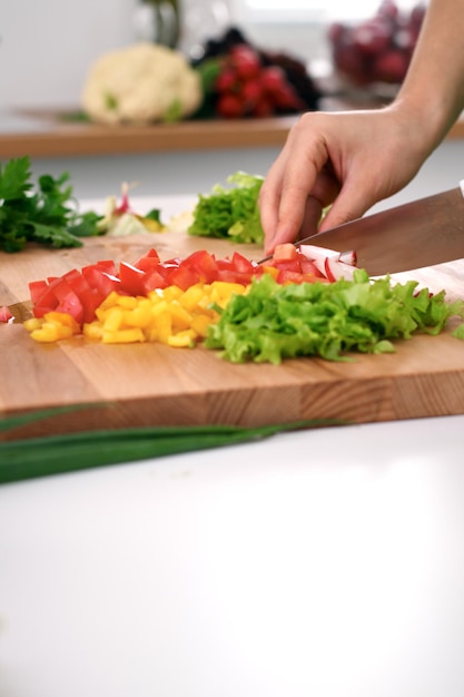 Nahaufnahme der Hände der Frau, die in der Küche kochen. Hausfrau, die frischen Salat schneidet. Vegetarisches und gesundes Kochkonzept.