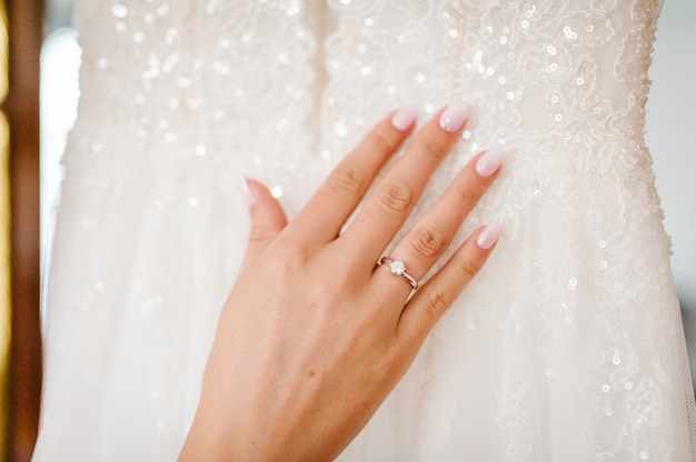 Nahaufnahme der Hände der Frau mit elegantem Diamantring am Finger, Liebes- und Hochzeitskonzept. Verlobungsring am Finger der Braut. Hochzeitstag. Weicher und selektiver Fokus.