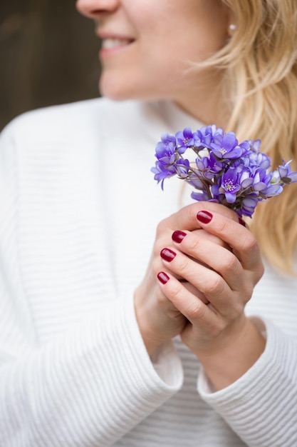 Nahaufnahme der Hände der Frau mit kleinen Haufen von schönen blauen Schneeglöckchen Frühlingsstimmung Mädchen mit Blumen