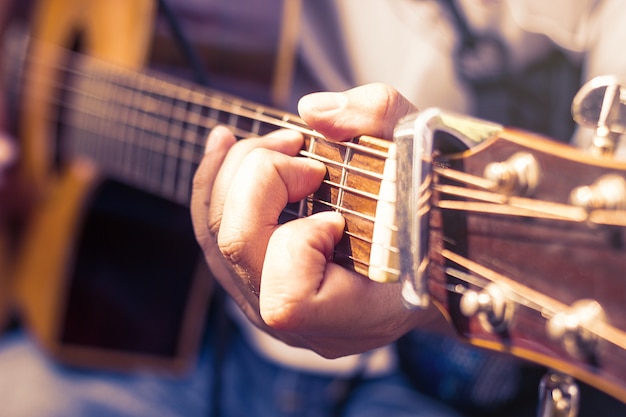 Nahaufnahme der Hände des Mannes, die Akustikgitarre spielen