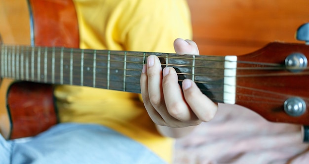 Nahaufnahme der Hände des weißen Jungen, die Gitarrenakkorde halten