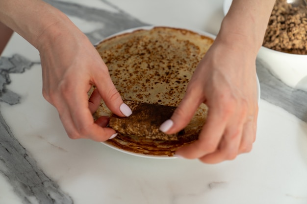 Nahaufnahme der Hände, die die Füllung in einen Pfannkuchen einwickeln