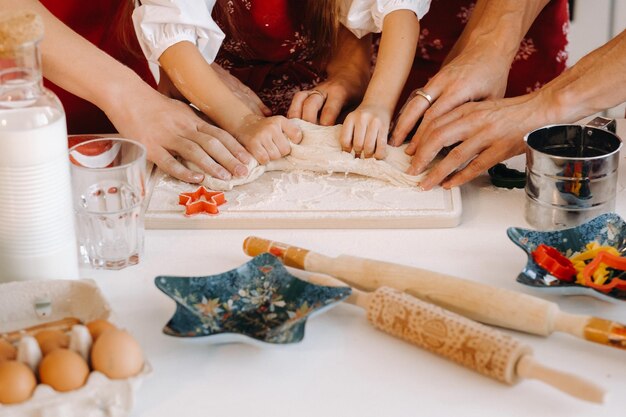 Nahaufnahme der Hände, die Teig auf dem Weihnachtsküchentisch kochen