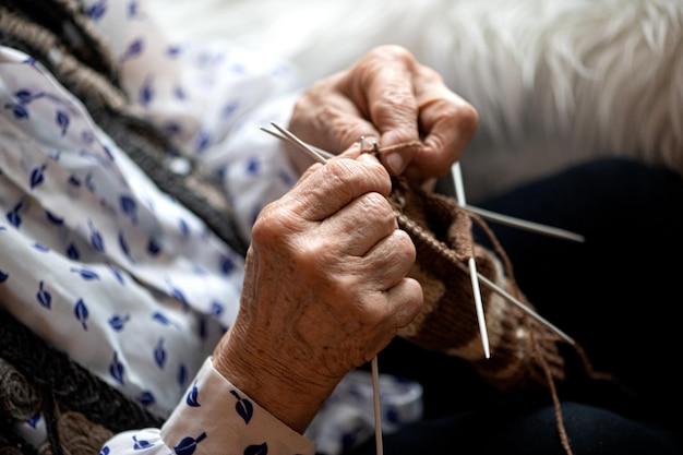 Nahaufnahme der Hände einer älteren Frau beim Stricken