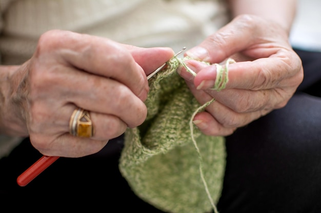 Nahaufnahme der Hände einer älteren Frau, die strickt