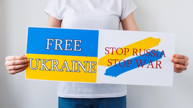 Nahaufnahme der Hände einer Frau hält ein Plakat mit dem Bild der ukrainischen Flagge, die besagt, dass freie Ukraine den Krieg beendet