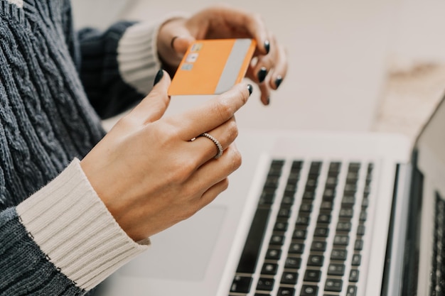 Nahaufnahme der Hände einer jungen Frau, die eine Kreditkarte für Online-Shopping liest