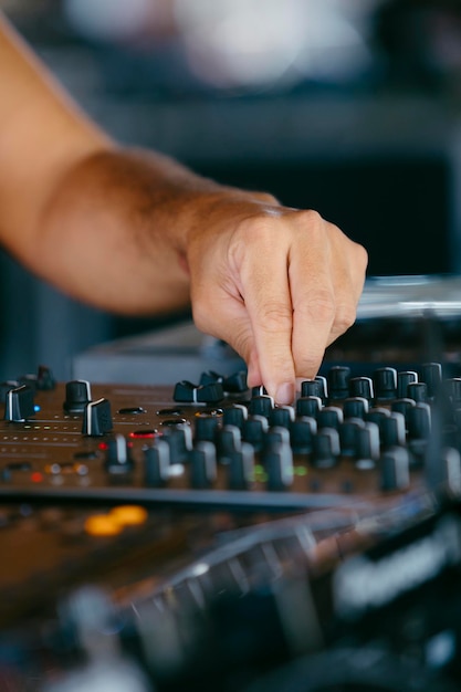 Nahaufnahme der Hände eines DJs, der den Mixer spielt, während er auf einem Musikfestival auftritt