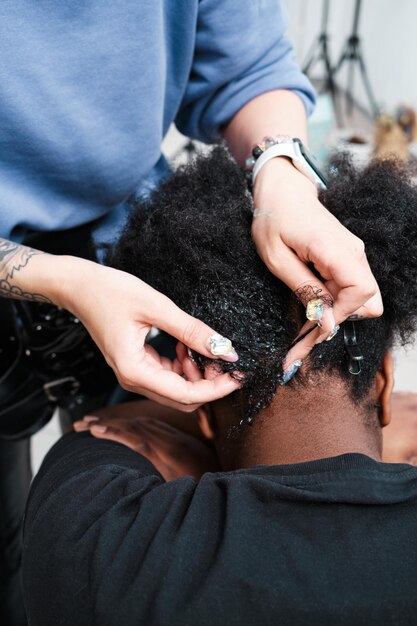 Foto nahaufnahme der hände eines friseurs, der die haare einer afro-frau frisuriert