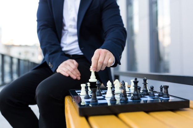 Nahaufnahme der Hände eines Geschäftsmannes, die sich auf einem Schachbrett bewegen, männlicher Geschäftsmann, der Schach spielt