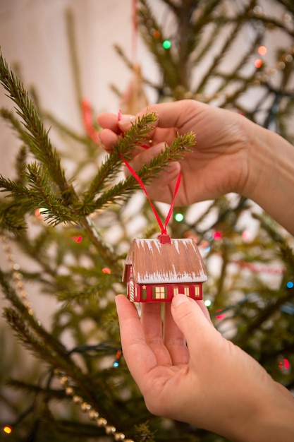 Foto nahaufnahme der hände eines jungen mädchens, das stilvolle weihnachtsdekorationen für einen weihnachtstannenbaum hält