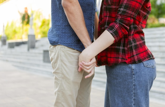 Nahaufnahme der Hände eines jungen Paares, das sich draußen hält. Liebeskonzept